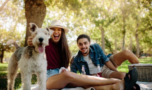 a man and woman sitting in park with a dog